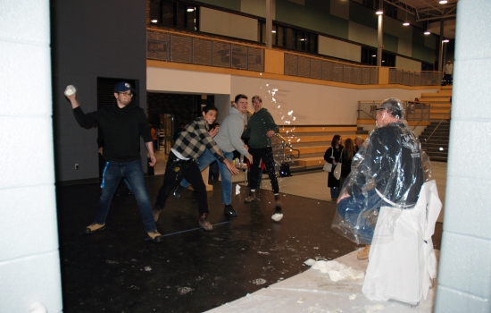 3 students throw pie at a faculty member