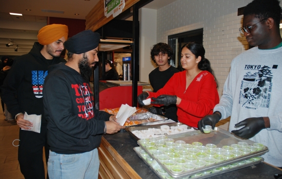Harnoor and student staff hand out treats at the Grab N' Go Kiosk
