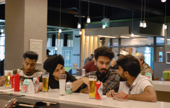 Four students sitting at the bar discuss a trivia question