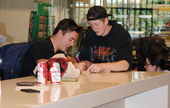 Two students sitting at the bar discuss a trivia question