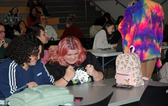 Students sitting at a table in the SLC and laughing with Sabin in the background