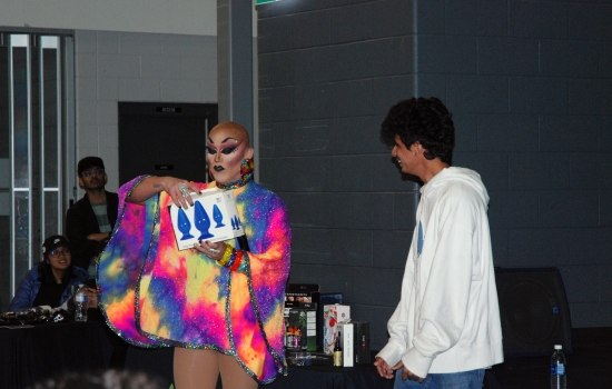 Sabin holds up a box of 3 large butt plugs while a student waits to receive his prize. 