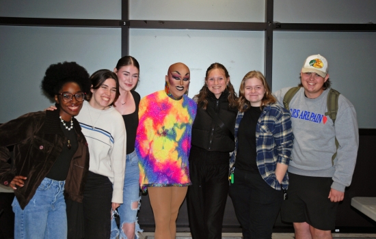 A group of students smiling with Sabin in the hallway