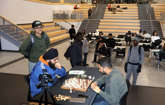 Rishi vs student chess game on the SLC stage with onlookers