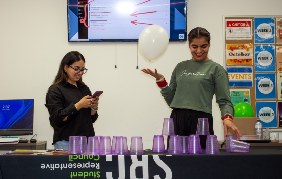 A student attempts to stack cups while keeping a balloon up in the air
