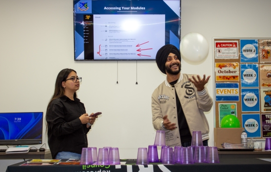 A student attempts to stack cups while keeping a balloon up in the air