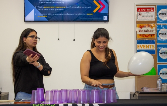 A student attempts to stack cups while keeping a balloon up in the air