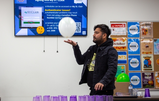 A student attempts to stack cups while keeping a balloon up in the air
