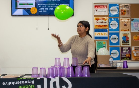 A student attempts to stack cups while keeping a balloon up in the air