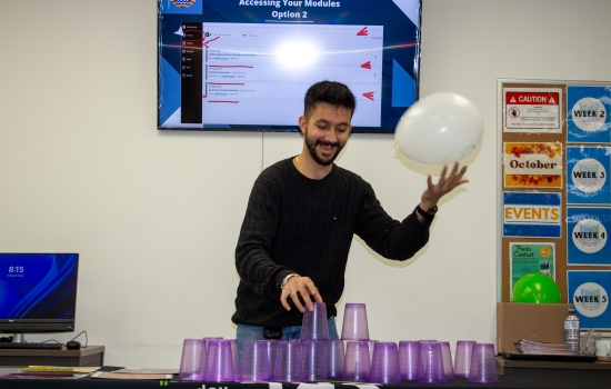 A student attempts to stack cups while keeping a balloon up in the air