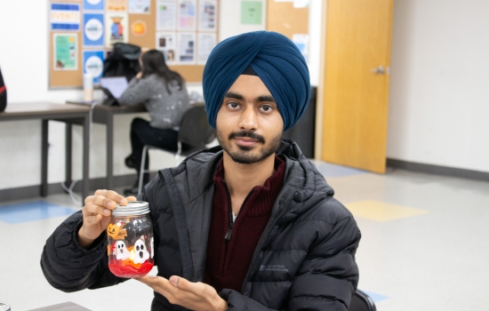 A student proudly shows off his painted ghost and pumpkin jar