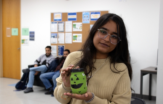 A student proudly shows off her green jackolantern jar