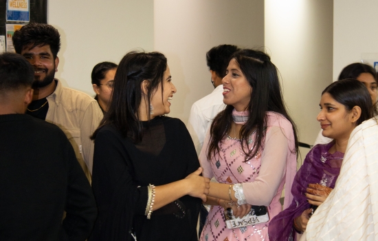 Two students in traditional dress looking at each other and smiling