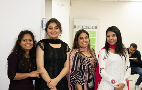 Four students stand together and post for a photo
