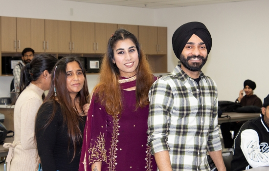 Three students stand together and post for a photo