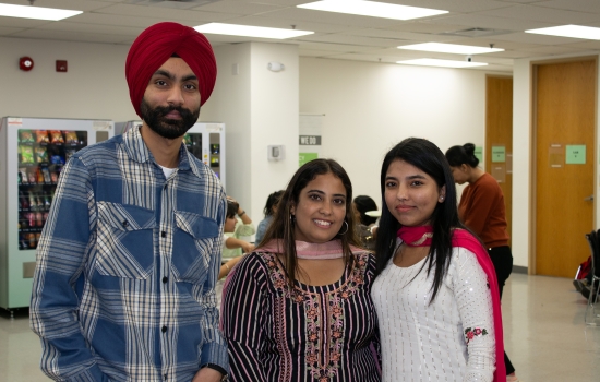 Three students stand together and post for a photo