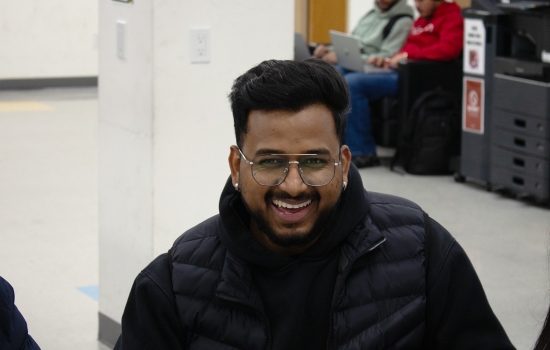 A student smiles for the camera as he begins his artwork