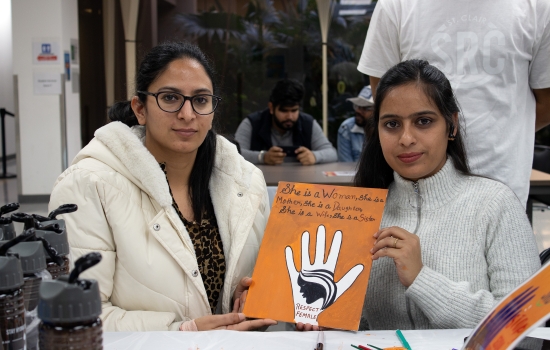 Two students show off their art piece for the camera