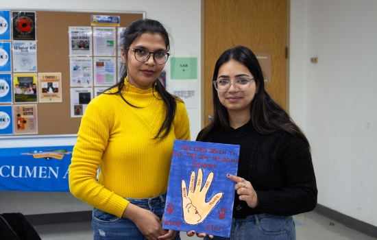Two students show off their art piece for the camera