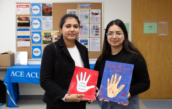 Two students show off their art pieces for the camera