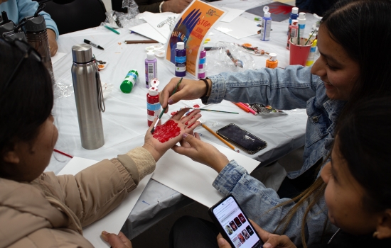 Two students help their friend paint her palm red