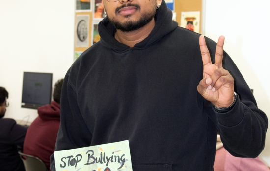 A student shows off his artwork which features a handprint with the text "Stop Bullying"