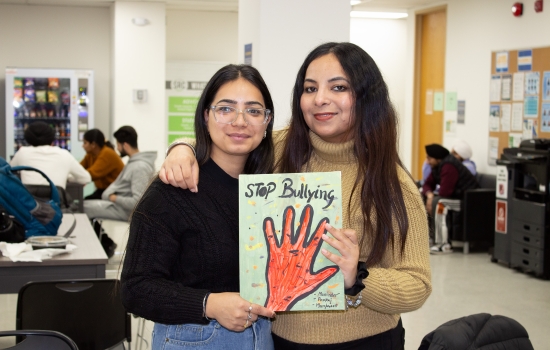 Two students show off their art piece for the camera