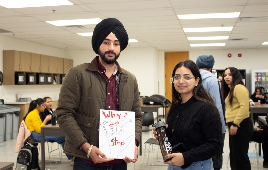 A students shows off his art piece for the camera while Sakshi holds an SRC water bottle to give him