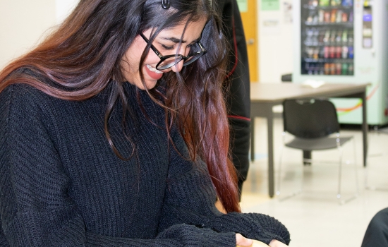A student uses a balloon to attempt to blow the cards off the water bottle
