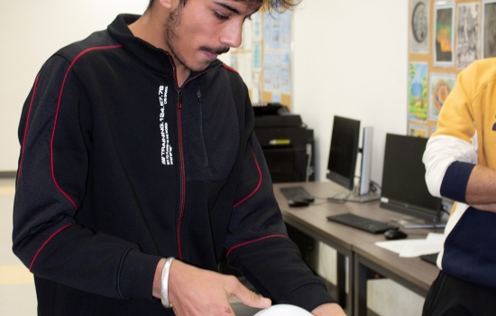 A student uses a balloon to attempt to blow the cards off the water bottle