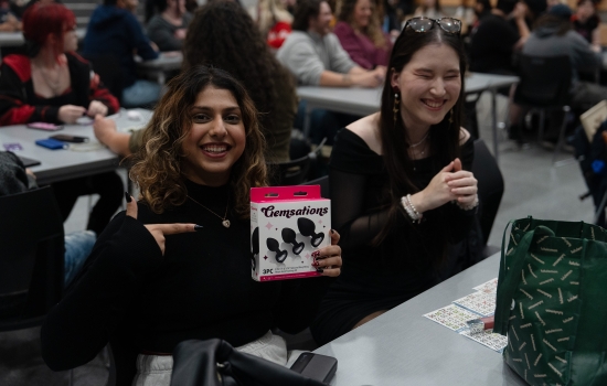 A student smiles and holds up her prize (butt plugs!)
