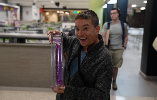 A winner holds up their prize (a double-sided dildo!)