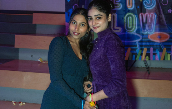 Two students pose in front of the backdrop