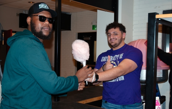 Ali hands cotton candy to a student