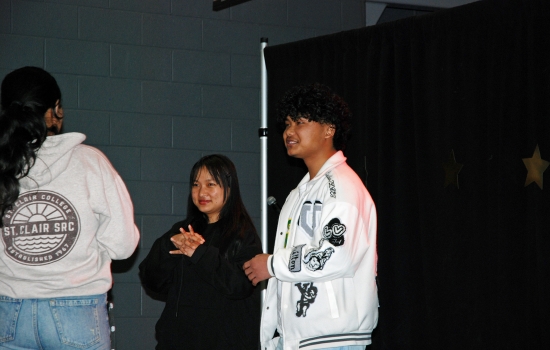 A group of students stands on the SLC stage