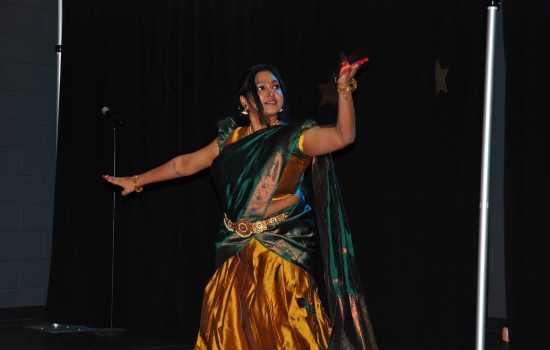 A student in traditional Indian dress dances on the SLC stage