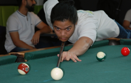 A student lines up their shot on the pool table