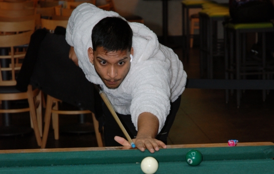 A student lines up their shot on the pool table