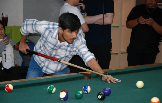 A student lines up their shot on the pool table
