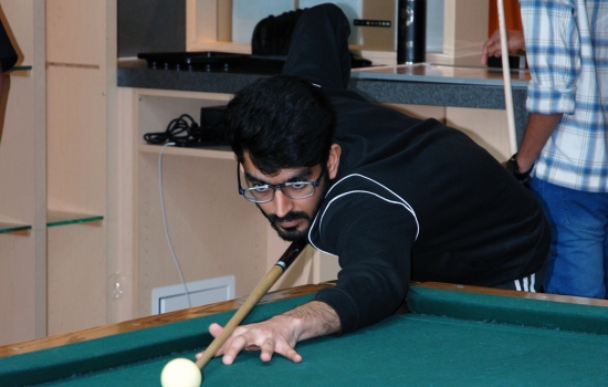 A student lines up their shot on the pool table