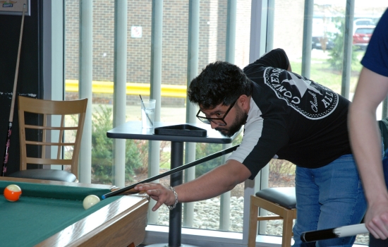 A student lines up their shot on the pool table