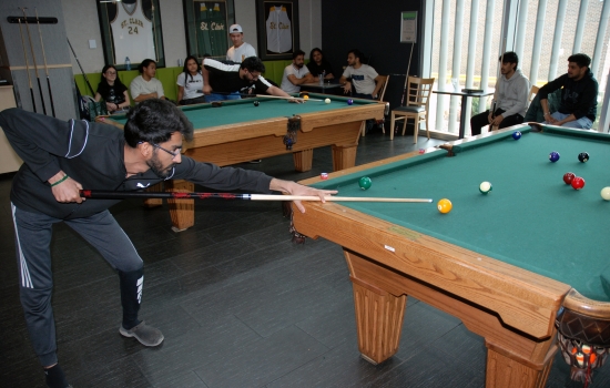 A student lines up their shot on the pool table