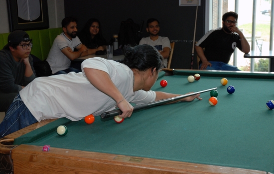 A student lines up their shot on the pool table