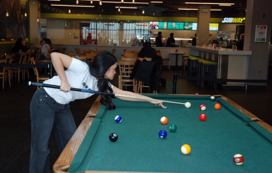 A student lines up their shot on the pool table