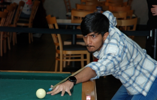 A student lines up their shot on the pool table