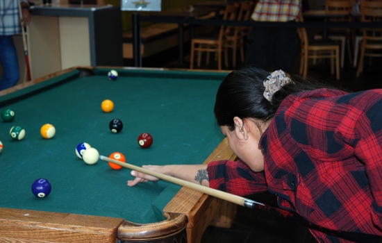 A student lines up their shot on the pool table