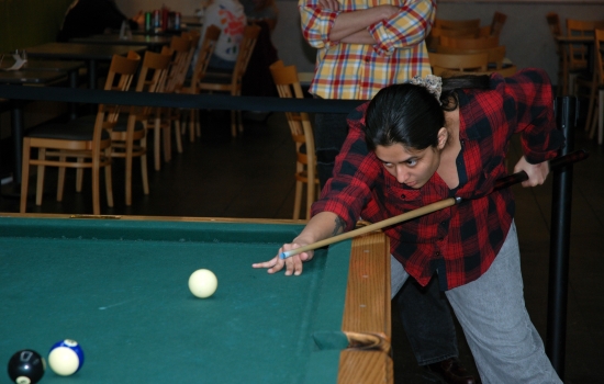 A student lines up their shot on the pool table