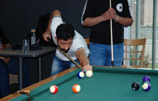 A student lines up their shot on the pool table