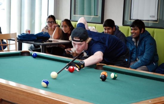 A student lines up their shot on the pool table