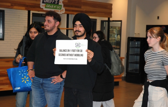 Pratham holds up a sign that says "balance on one foot for one minute without wobbling"